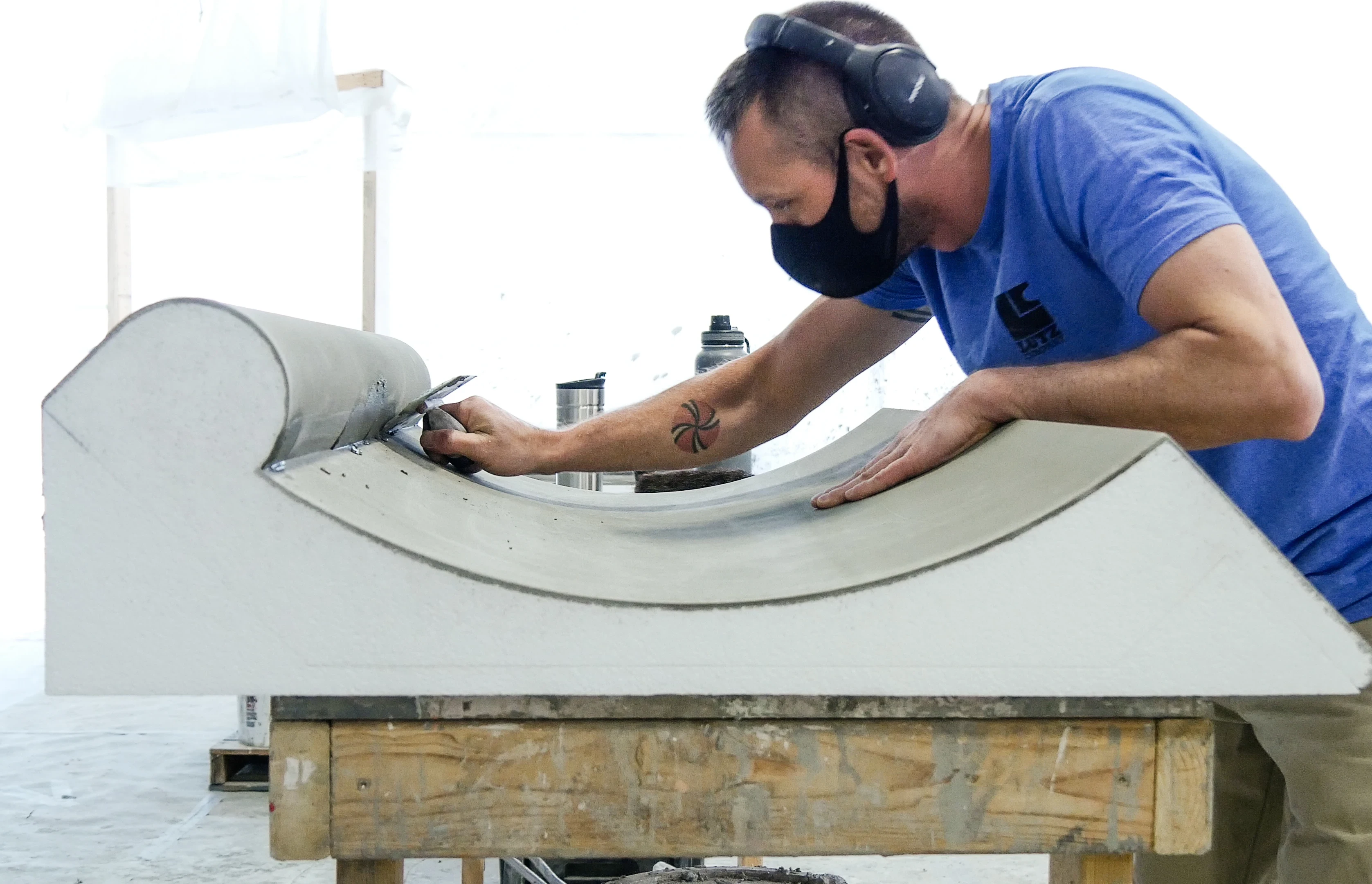 Worker applying finish to prefab wall panel in a factory.