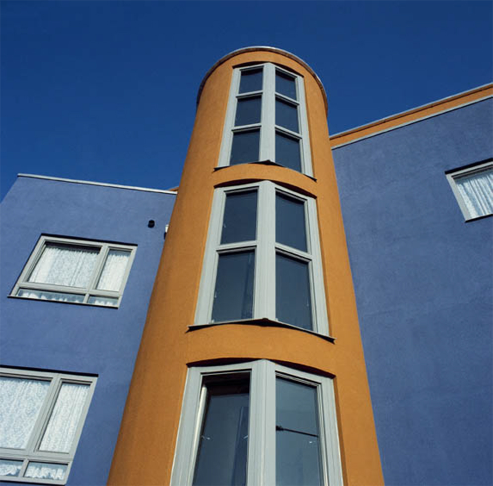 Side of a curved building with blue and gold finishes.