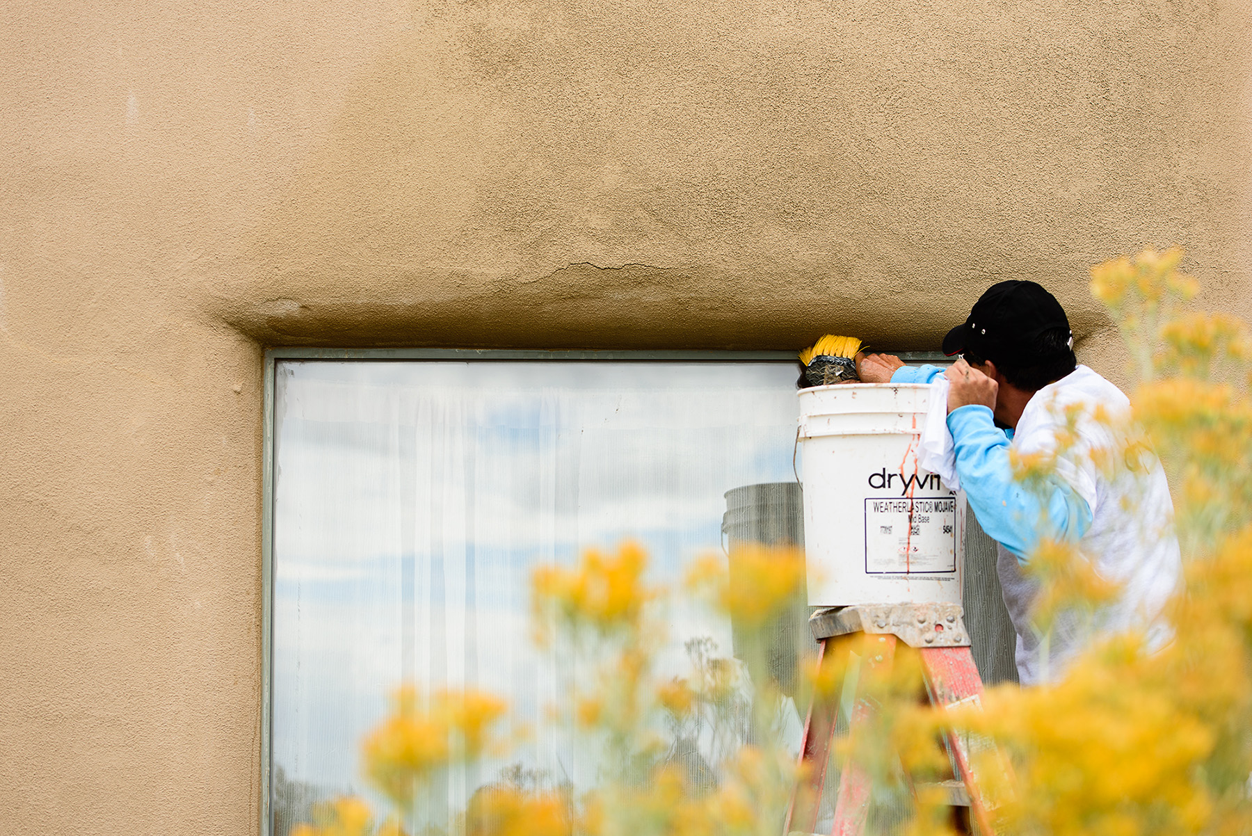 Worker brushing off EIFS wall to remove debris.
