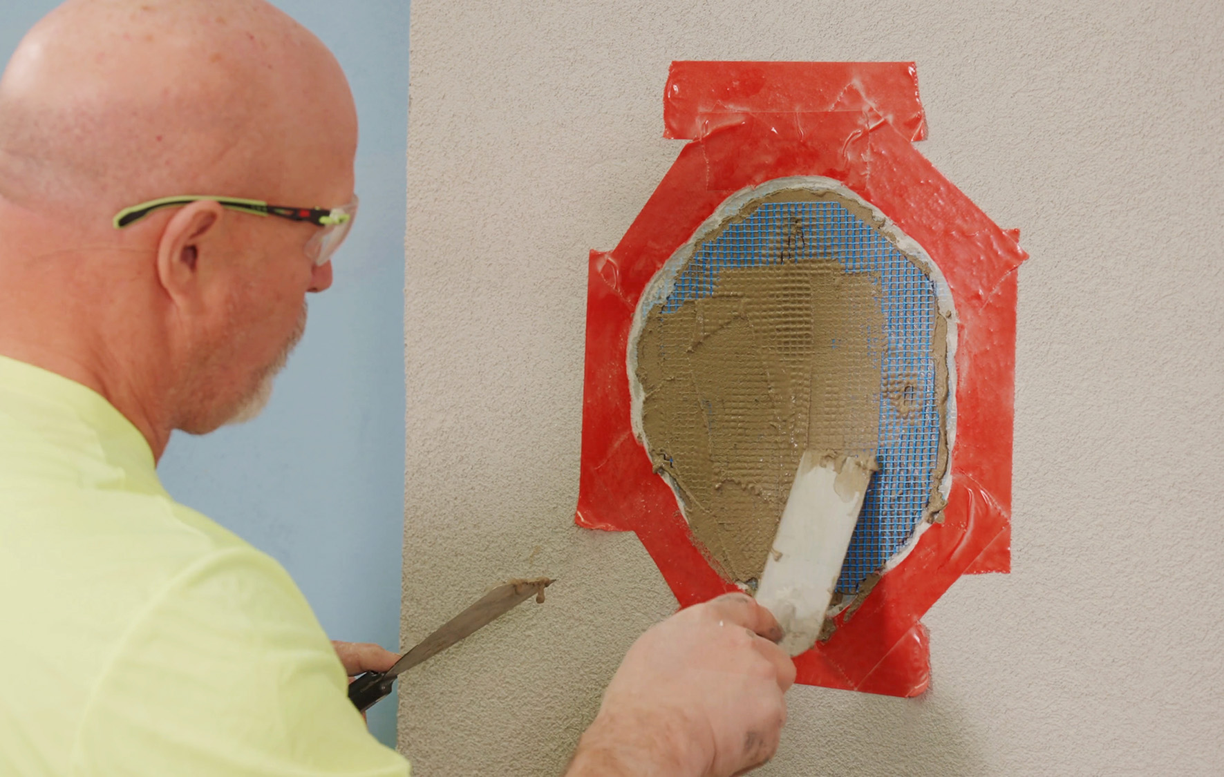 Repairing an EIFS wall with a trowel and patch.