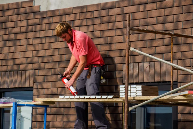 worker applying sealant to brick veneer