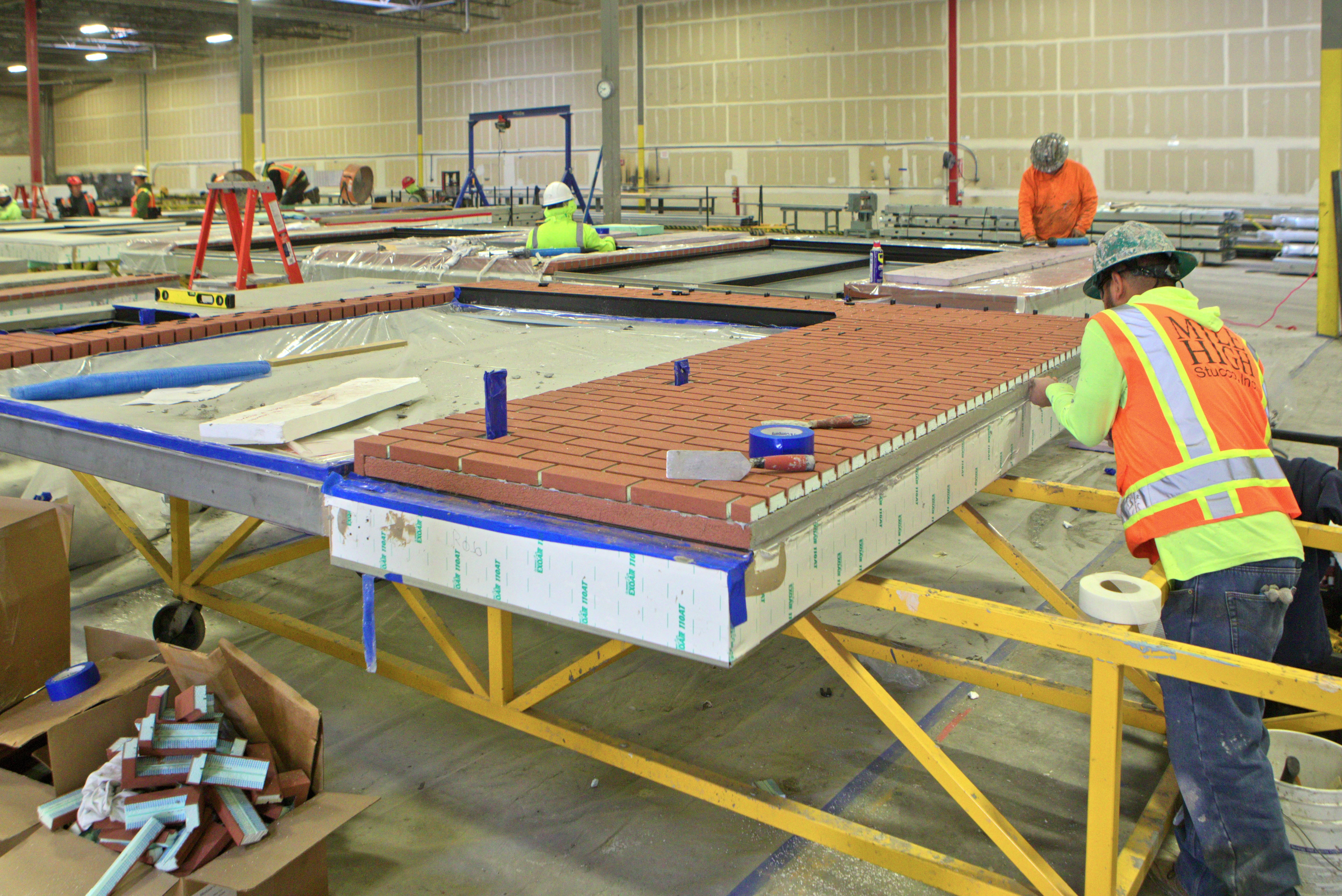 workers detailing prefab walls in a factory