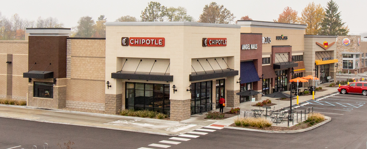 Exterior of strip mall with beige EIFS and insulated brick veneer.